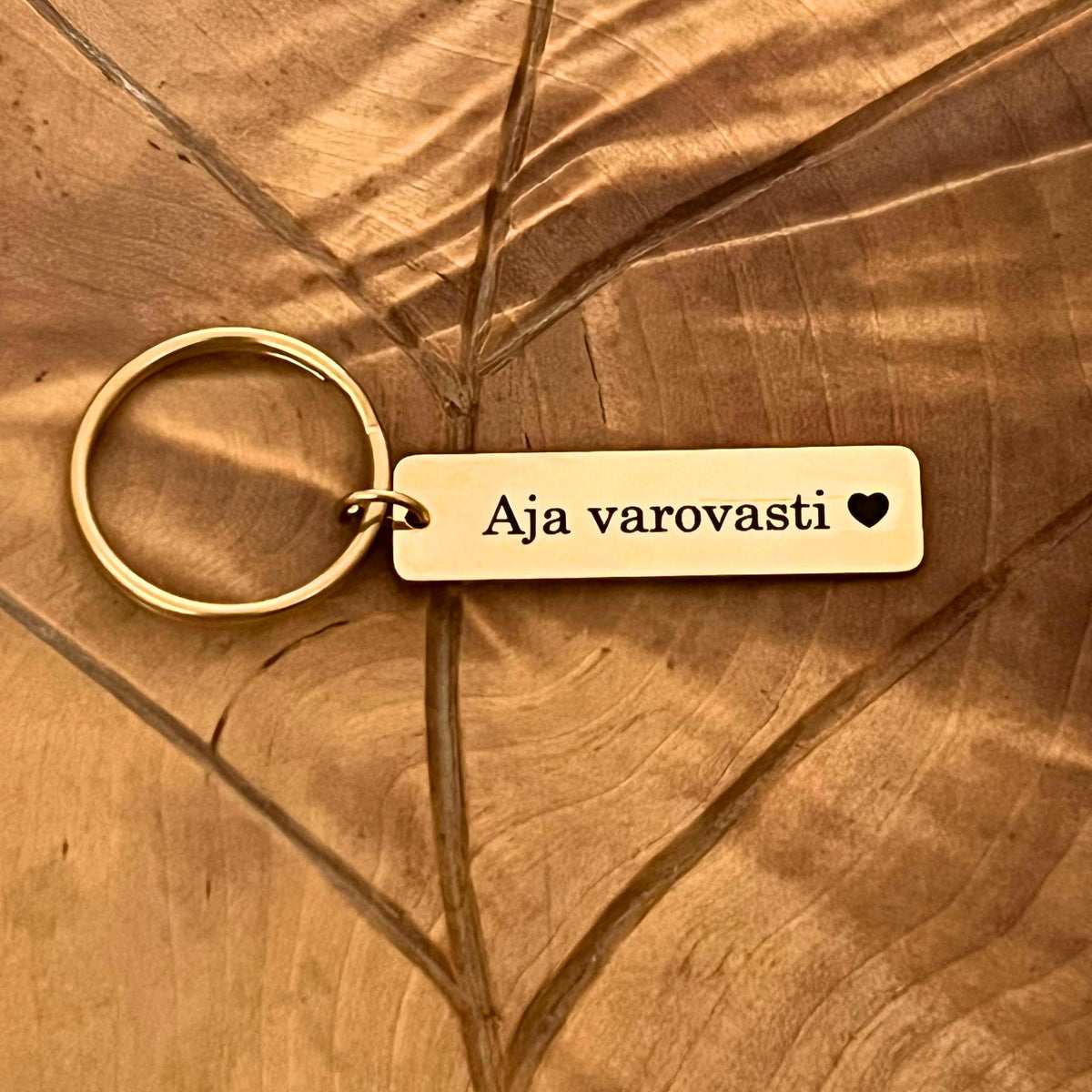 Kullanvärinen avaimenperä tekstillä Aja varovasti.