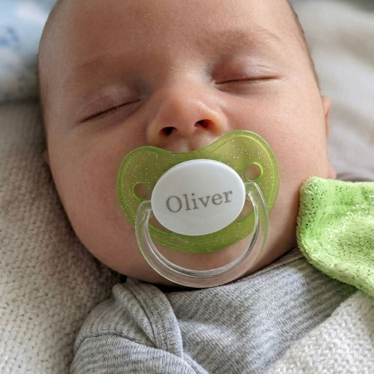 Oliverilla on suussa omalla nimellä oleva vihreän ja kimaltava nimitutti.