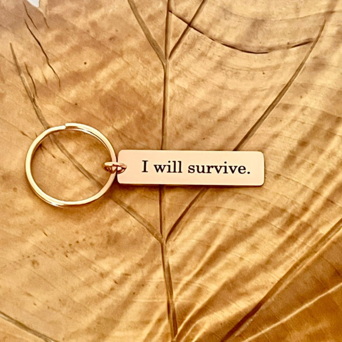 Ruusukullan värinen avaimenperä tekstillä I will survive