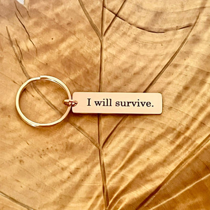 Ruusukullan värinen avaimenperä tekstillä I will survive