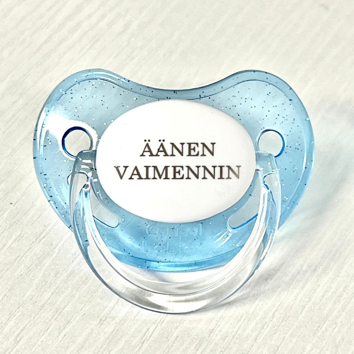 Sininen tutti vauvalle, jonka tekstissä lukee äänenvaimennin.