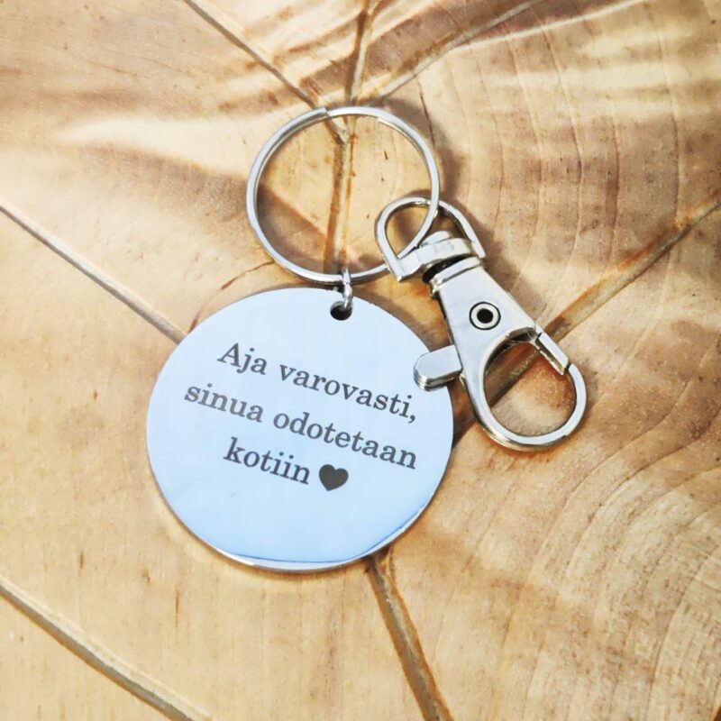Pyöreä avaimenperä tekstillä puualustalla